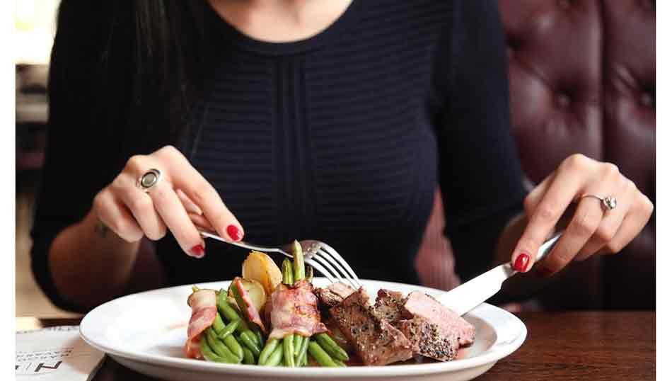 Comportamiento y saber estar en la mesa. Mujer tomando un alimento