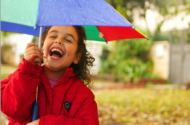 Niña sonriendo bajo la lluvia