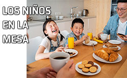 Dos niños sentados a la mesa con su familia